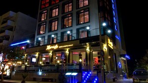 Un hotel con un letrero llamativo, un café y terraza.