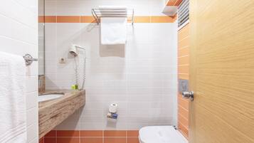 Un bagno con lavandino, specchio, portasciuga, water e soffione.