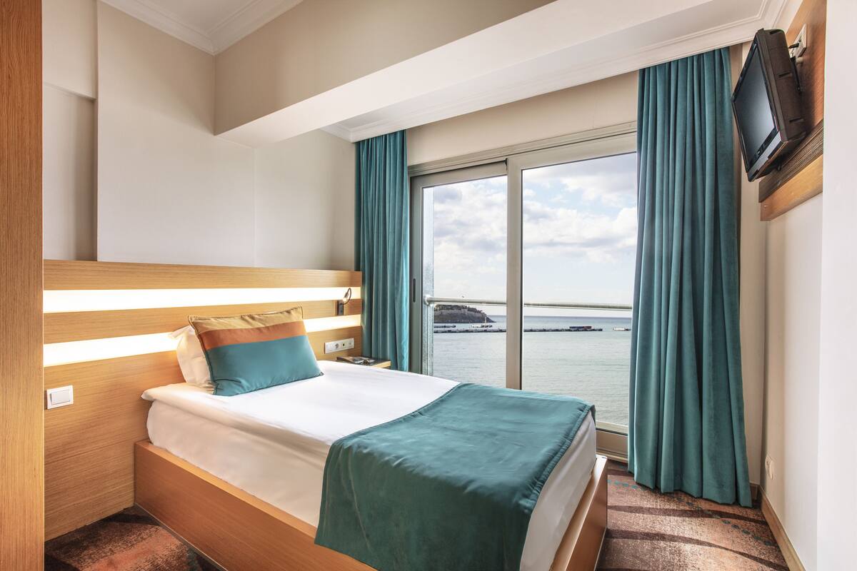 Ein Hotelzimmer mit Bett, Wandfernseher und Meerblick.