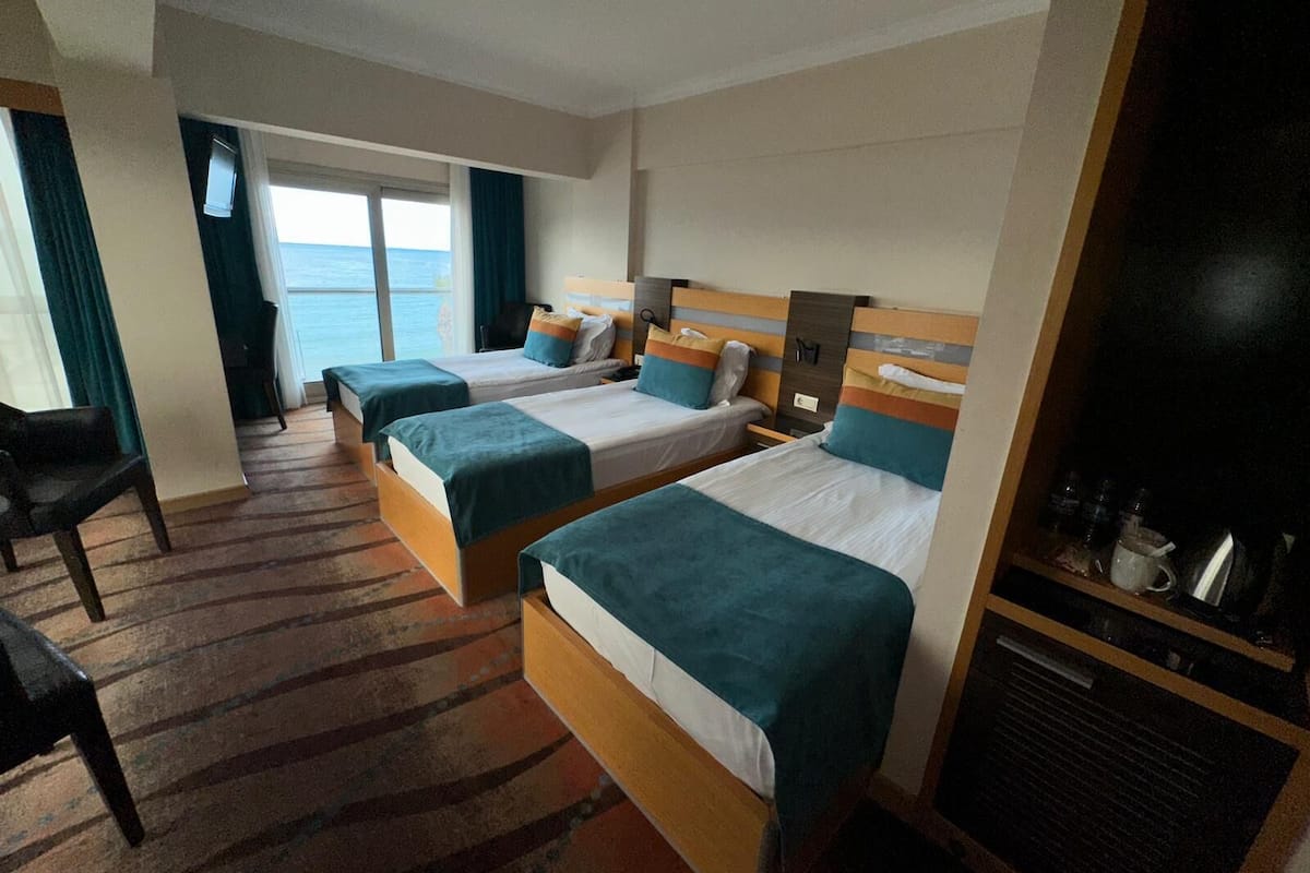 Ein Hotelzimmer mit zwei Betten, einem Schreibtisch und Meerblick.