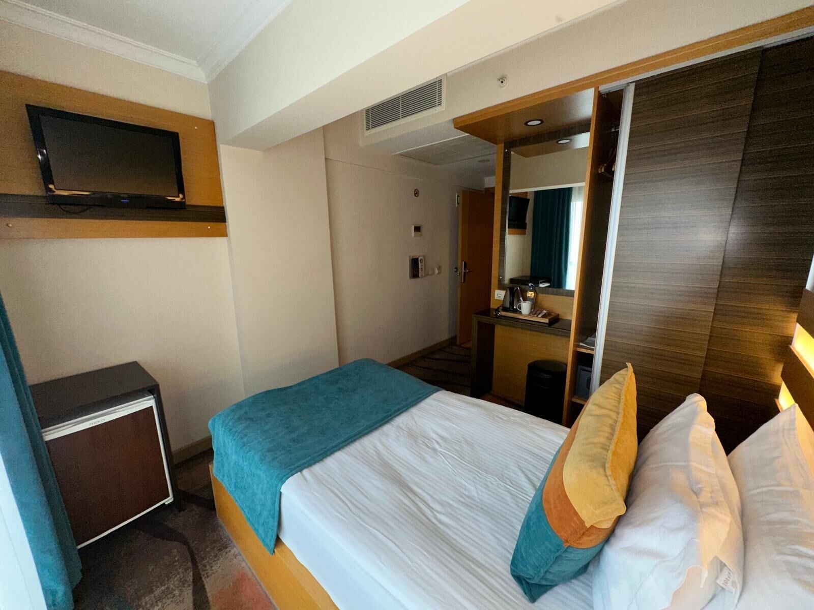 Een hotelkamer met een bed, een bureau, een televisie en een spiegel.