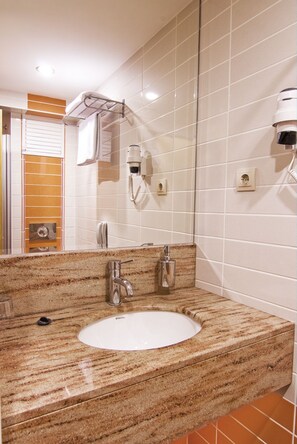 A bathroom with a granite sink, a mirror, a towel rack, and a hairdryer.