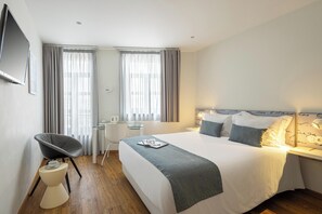 A modern hotel room with a bed, bedside table, chair, desk, and curtains. - Hotel das Salinas (Aveiro)