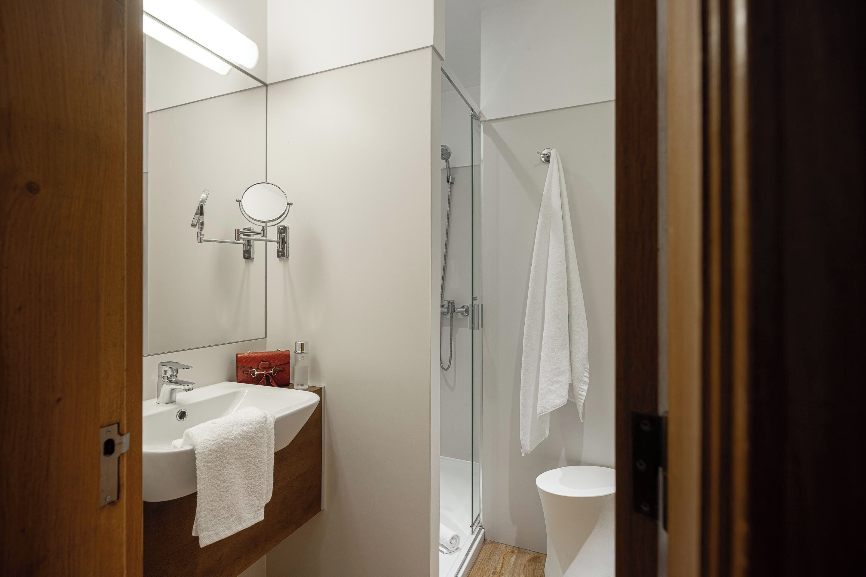 A bathroom with a sink, mirror, and glass shower enclosure.