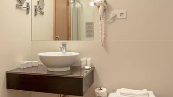 A bathroom with a white sink, a large mirror, a hairdryer, and a towel rack.