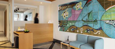 A reception area with a wooden desk, a blue sofa, and a colorful abstract mural on the wall.