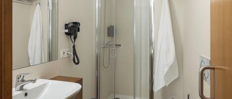 A bathroom with a glass shower enclosure, a sink, a bidet, and a towel rack.