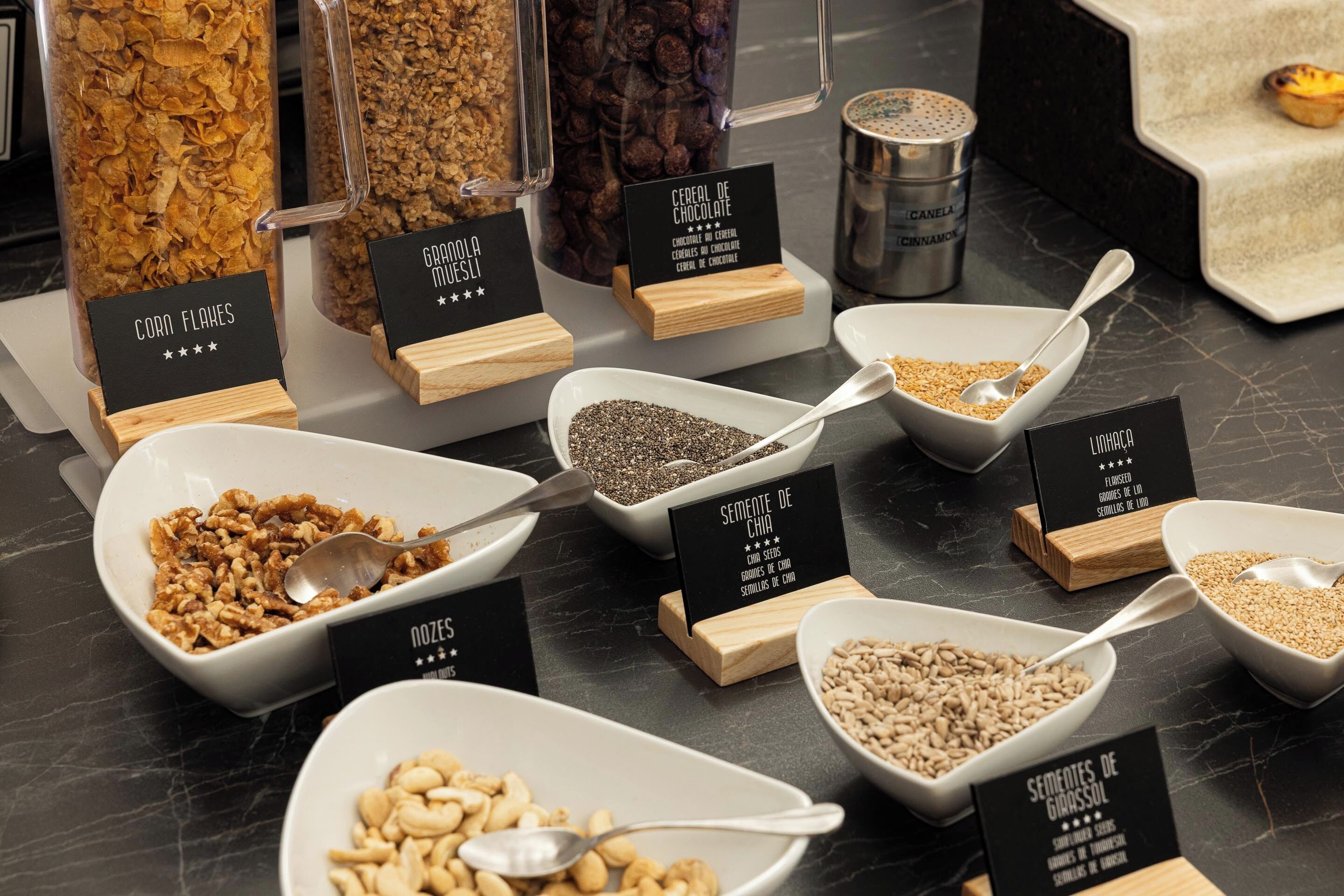 A variety of cereal and grain bowls with spoons and labeled signs indicating different types.