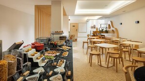 Un comedor con mesas y sillas de madera, y una barra de estilo bufé.