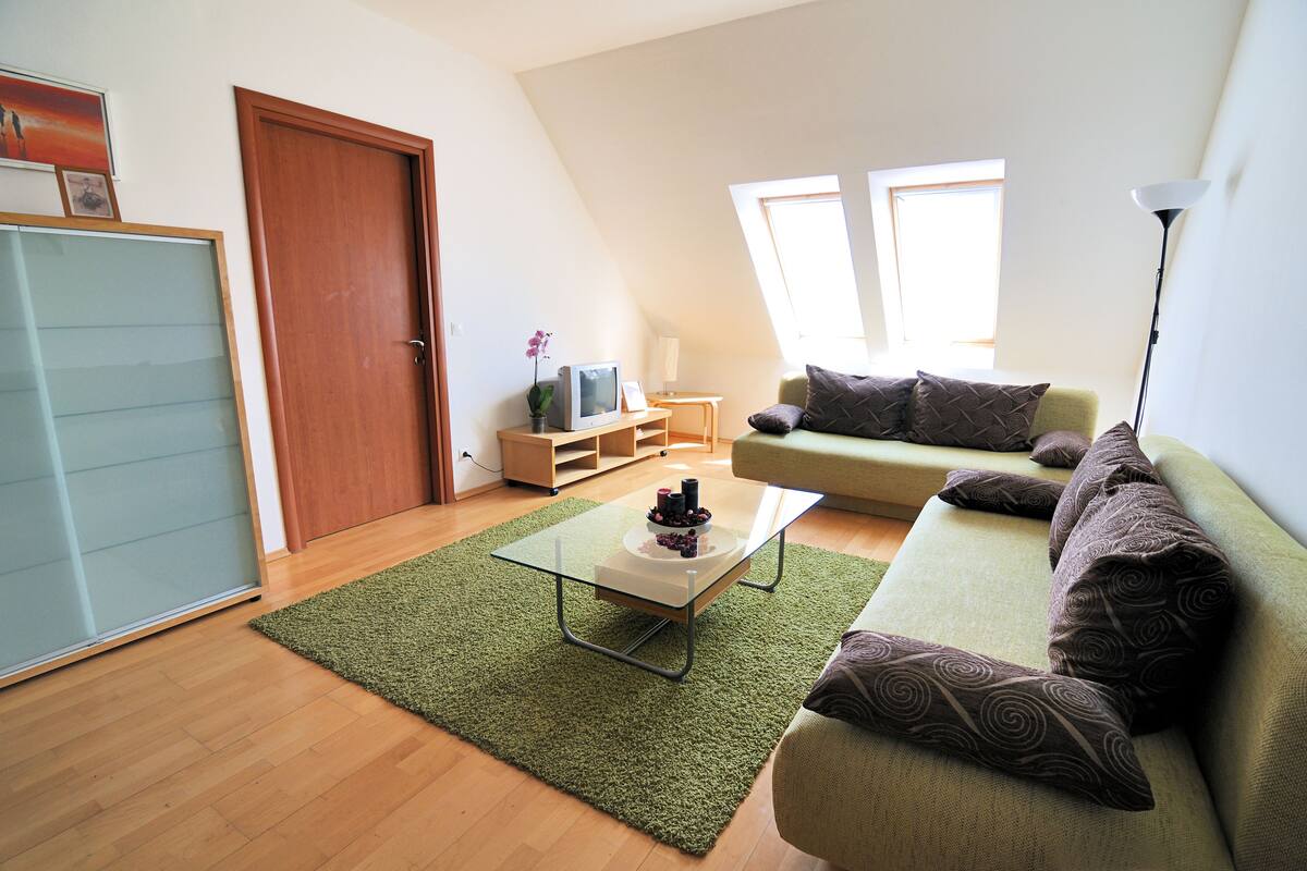 Una sala de estar con una mesa de centro de vidrio, un sofá verde y una puerta de madera.