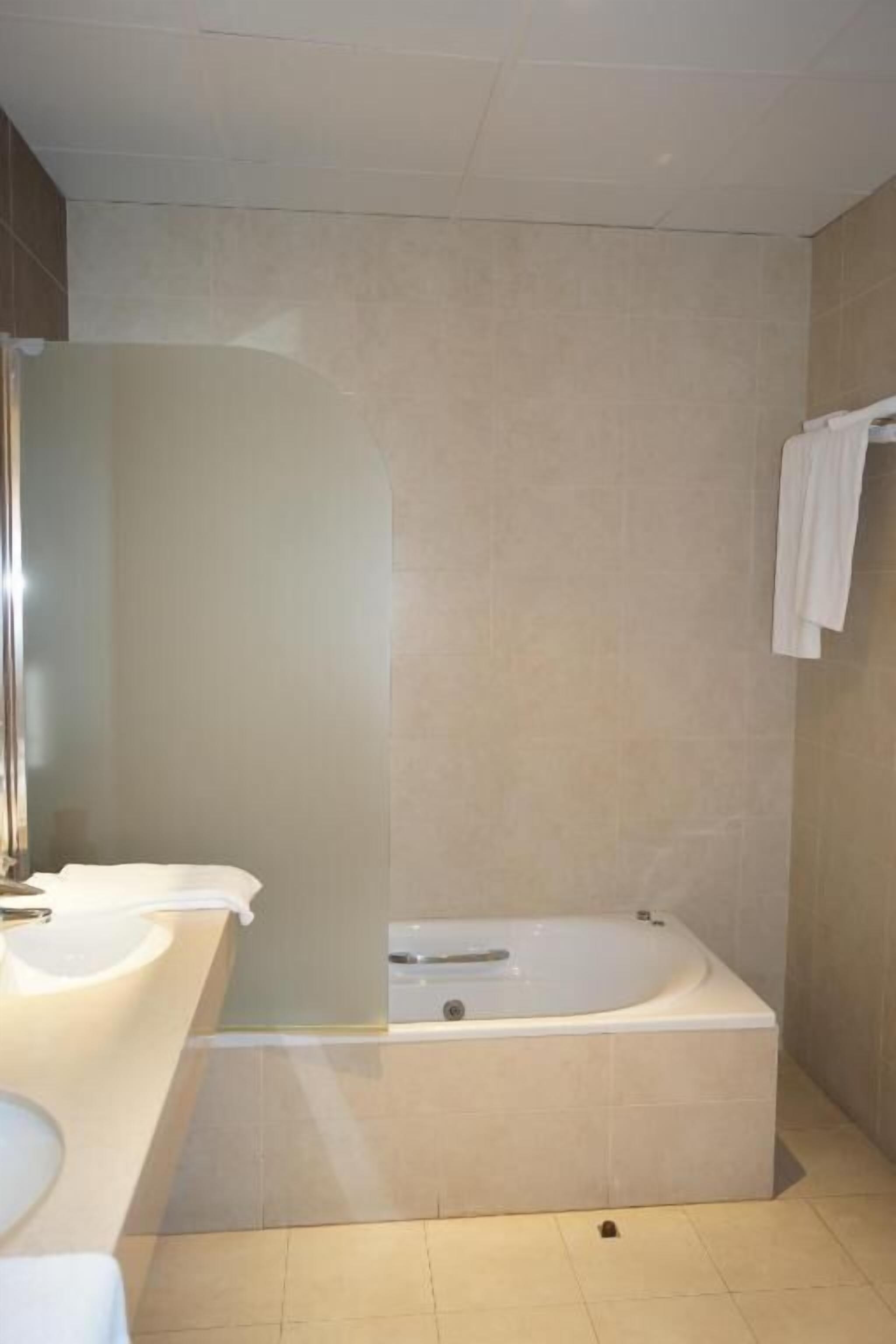 Un baño moderno con bañera, dos lavamanos y un espejo.