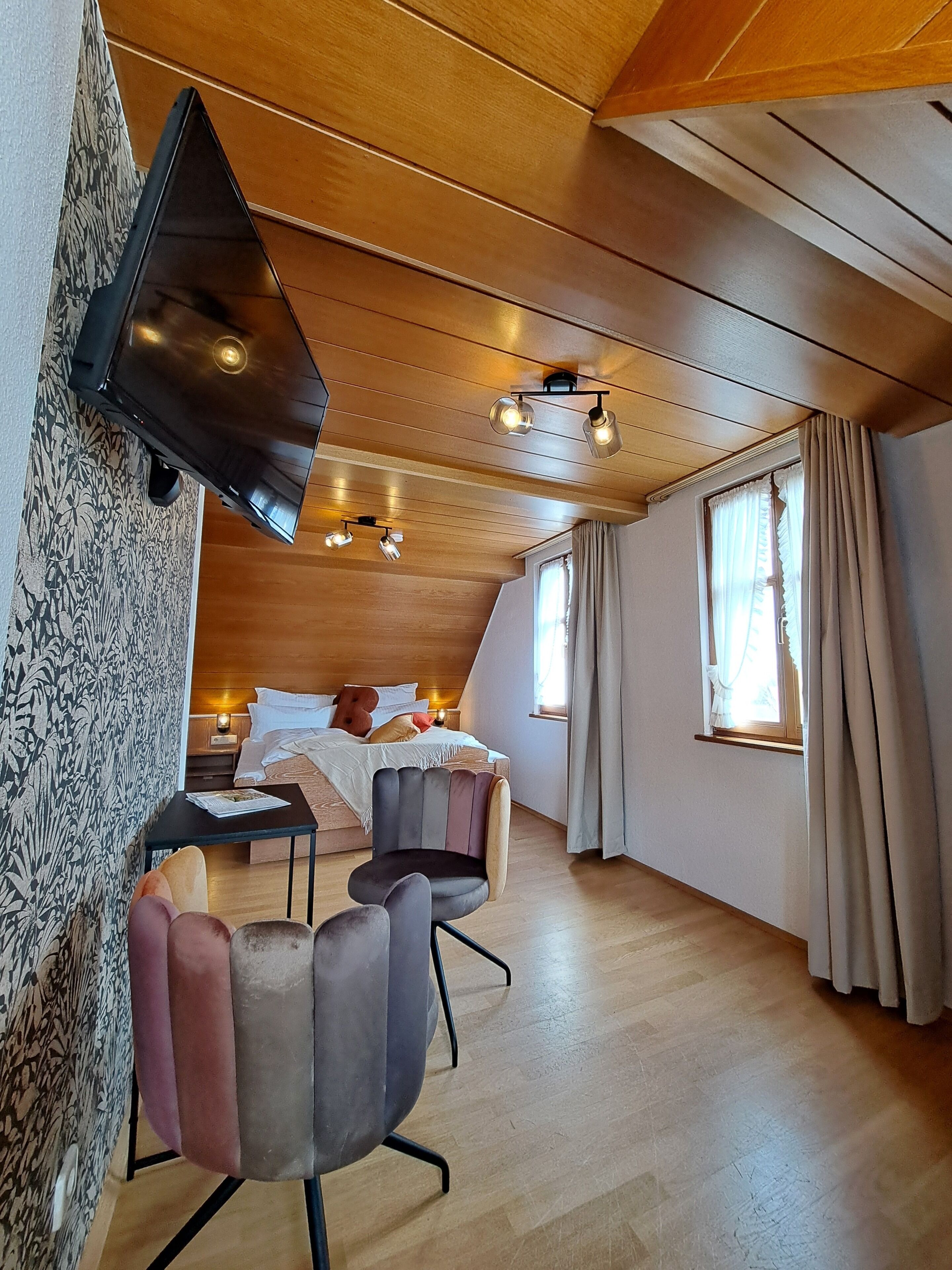 A cozy room with a bed, a desk, and two chairs.