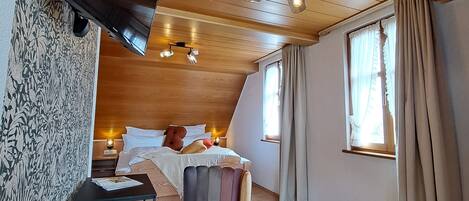 A cozy room with a bed, a desk, and two chairs.