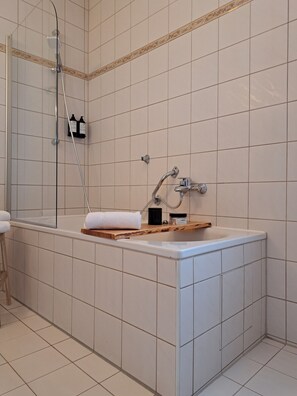 Ein Badezimmer mit Badewanne, Dusche und Waschtisch mit Spiegel.