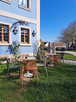 A building with outdoor seating, a garden, and a clear sky. - Gasthof Hotel Bezold (Rothenburg ob der Tauber)