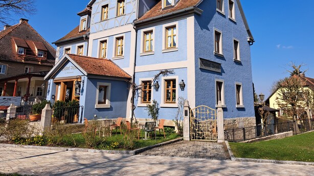 A large, multi-story building with a traditional architectural style, featuring a prominent entrance gate and a clear view of the surrounding area. - Gasthof Hotel Bezold (Rothenburg ob der Tauber)