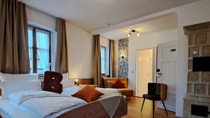 A spacious bedroom with a large bed, a wooden floor, a fireplace, and a view of the outdoors. - Gasthof Hotel Bezold (Rothenburg ob der Tauber)
