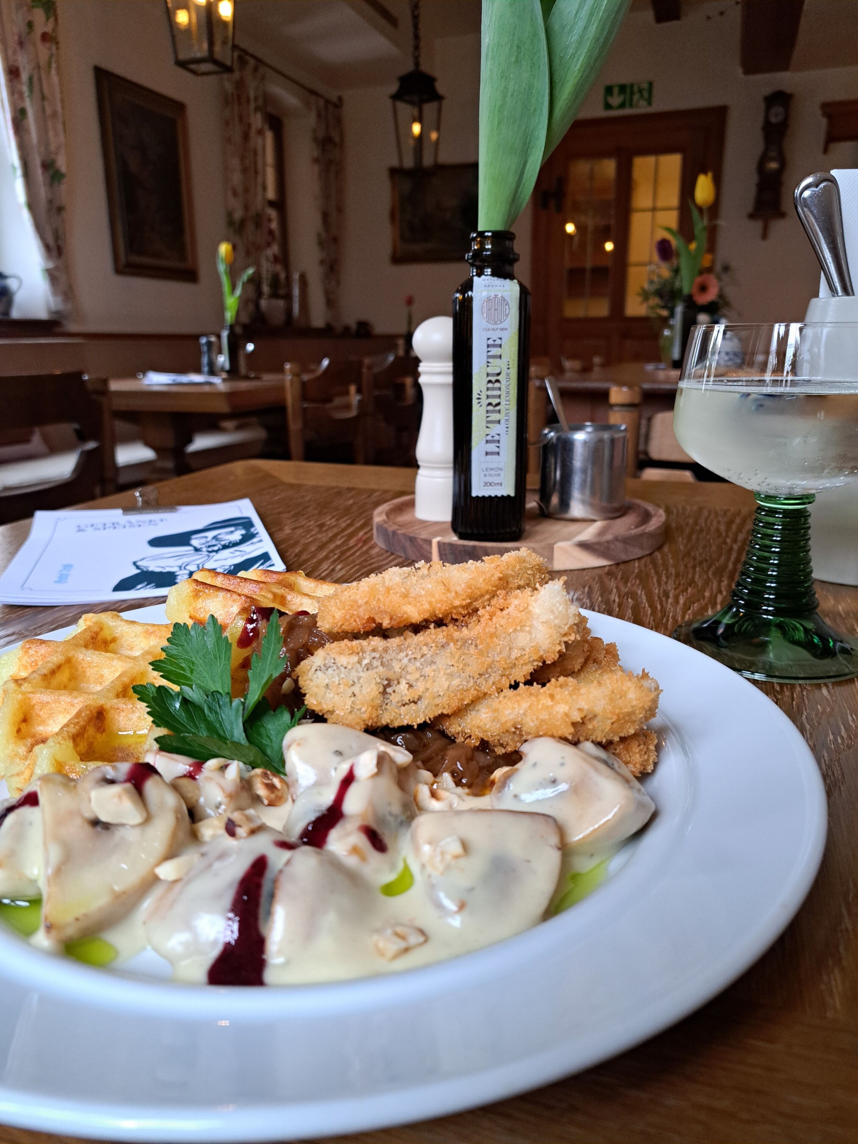 Ein Esstisch mit einem Teller Essen, einer Getränkeflasche und einem grünen Glas.