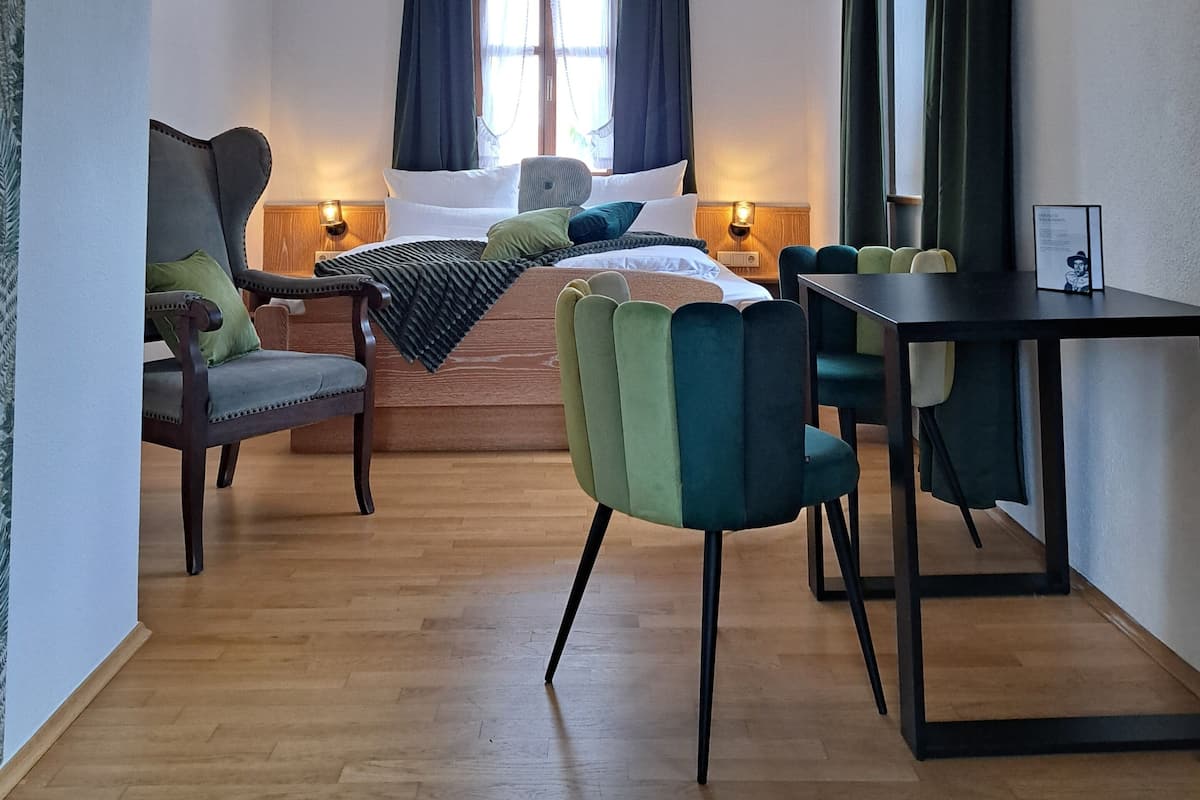 A hotel room with a bed, a desk, a chair, a window with curtains, and a ceiling light fixture.