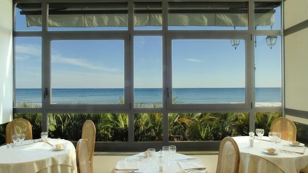 Un espace repas offrant une vue sur l’océan grâce à de grandes fenêtres.
