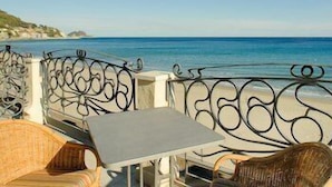 Une terrasse en bord de mer, avec une table et des chaises en osier, donnant sur l’océan.