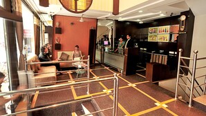 A hotel lobby with a reception desk, seating area, and a staircase. - Ratnawali (Jodhpur)