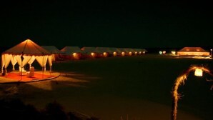 A row of tents with a central illuminated structure, likely a communal area, and a clear sky. - Ratnawali (Jodhpur)