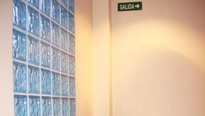 A room with a blue armchair, a glass partition wall, and a radiator. - Hotel Arteixo (Arteixo)