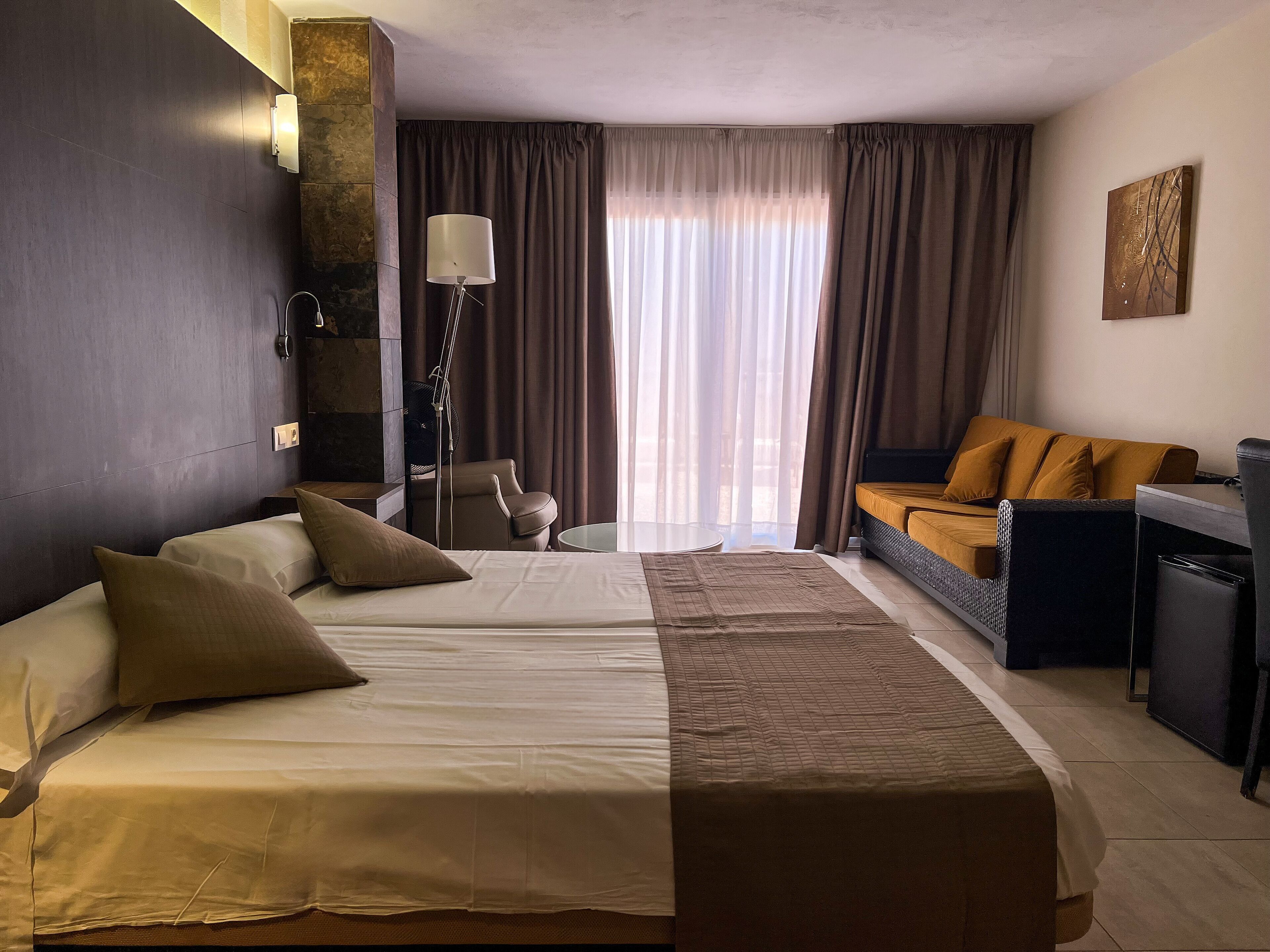 Quarto de hotel com uma cama grande, uma mesa, uma cadeira e um sofá.