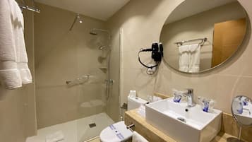 A modern bathroom with a glass-enclosed shower, a white sink with a mirror, and a toilet.