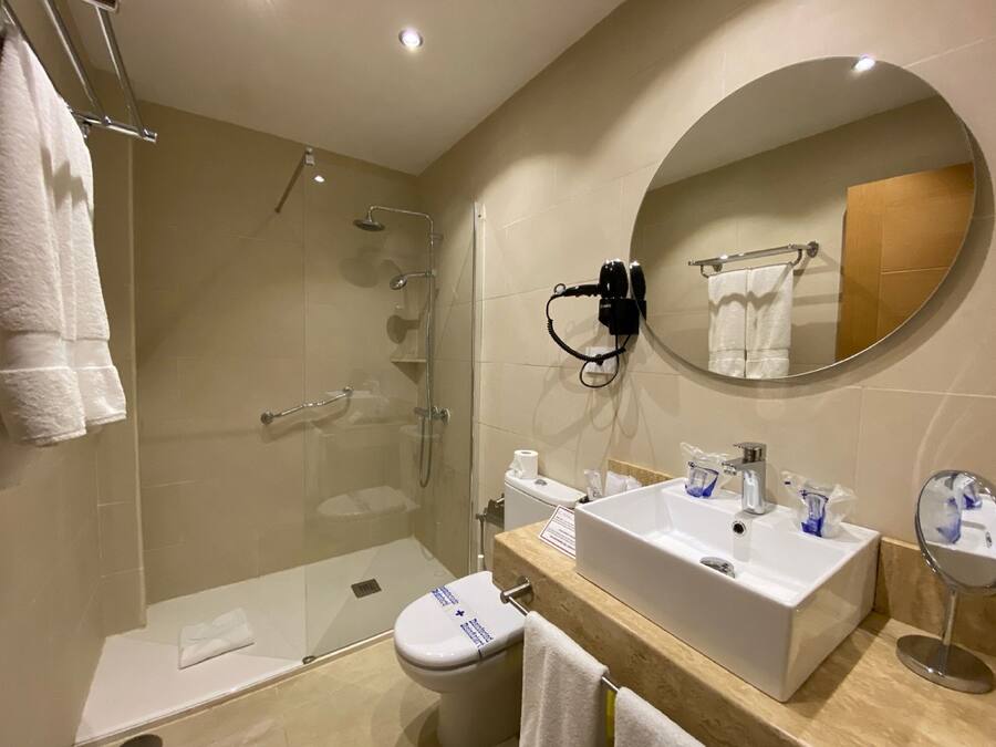 A modern bathroom with a glass-enclosed shower, a white sink with a mirror, and a toilet.