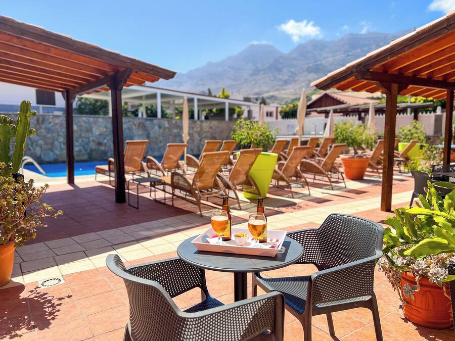 A patio area with outdoor seating, a pool, and mountains in the background.