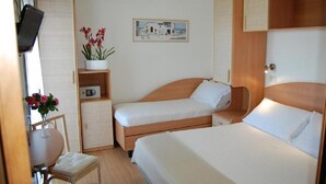 A compact hotel room with two single beds, a small table with a chair, a potted plant, a painting on the wall, and a wooden cabinet. - Hotel Rivazzurra (Pesaro)