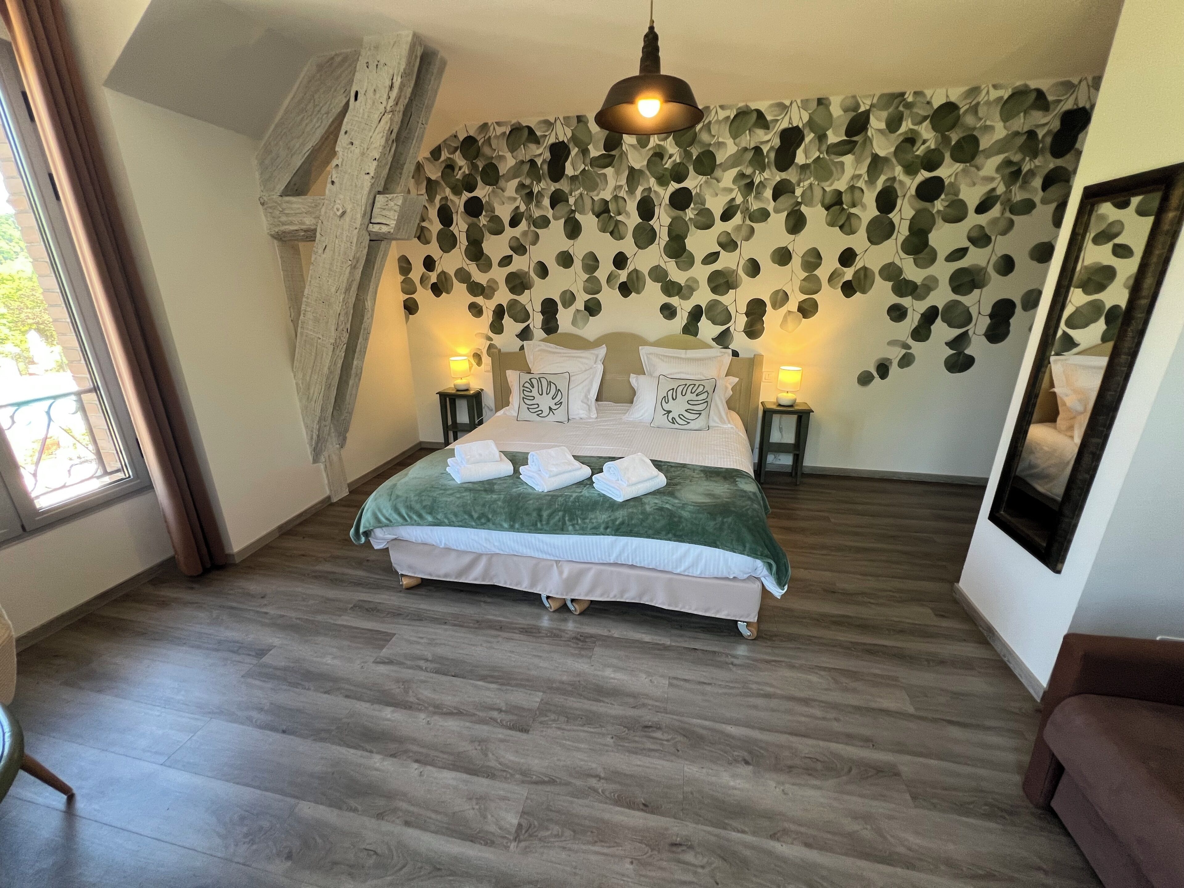 Een slaapkamer met een bed, een spiegel aan de muur en een raam met gordijnen.