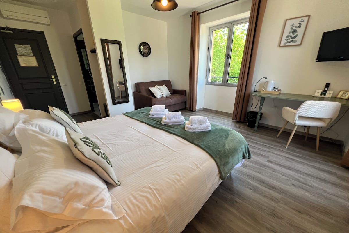 Une chambre d’hôtel avec un lit, un bureau, une chaise, une fenêtre et un téléviseur.