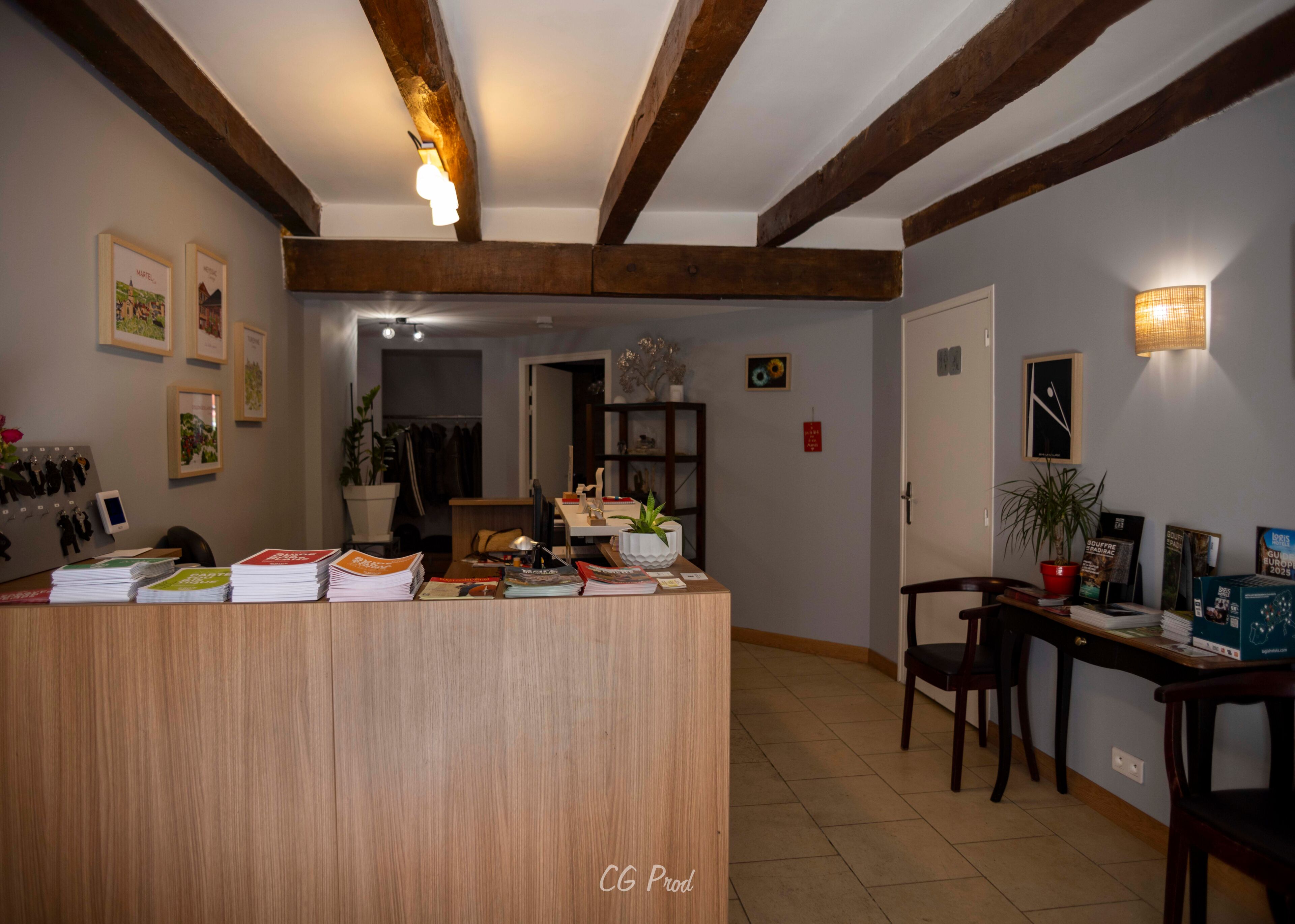 Ein Empfangsschalter mit Holzoptik, ein Blumentopf und eine Wand mit gerahmten Bildern.