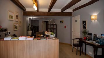 Ein Empfangsschalter mit Holzoptik, ein Blumentopf und eine Wand mit gerahmten Bildern.