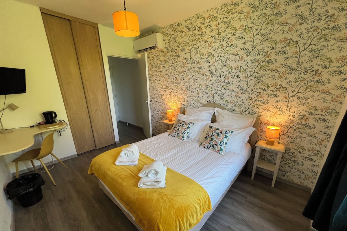 Une chambre d’hôtel comprenant un lit, deux lampes de chevet, un bureau avec une chaise et un téléviseur.