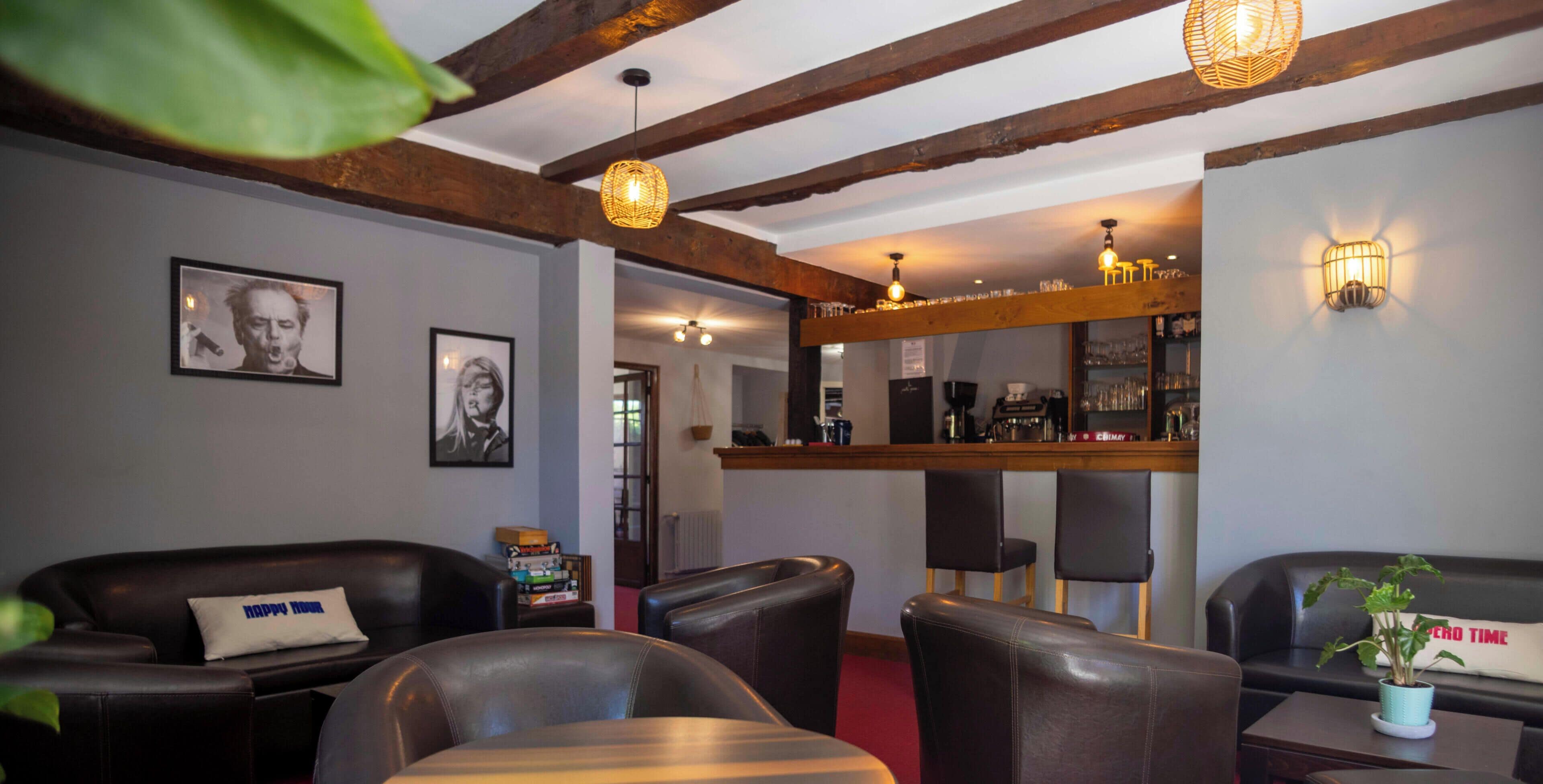A bar area with a wooden ceiling, bar stools, and a counter with various items.