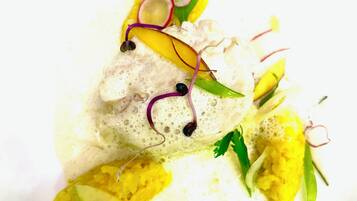 A white plate with a fish fillet, garnishes, and a creamy sauce.