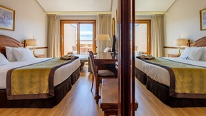 A hotel room with two beds, a desk, and a view of the sky through large windows. - Dorma Reina Isabel (Ávila)