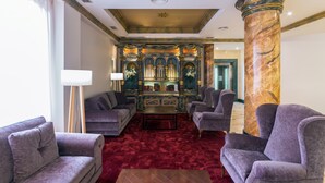 A luxurious lobby with plush seating, a marble column, and an ornate bookcase. - Dorma Reina Isabel (Ávila)