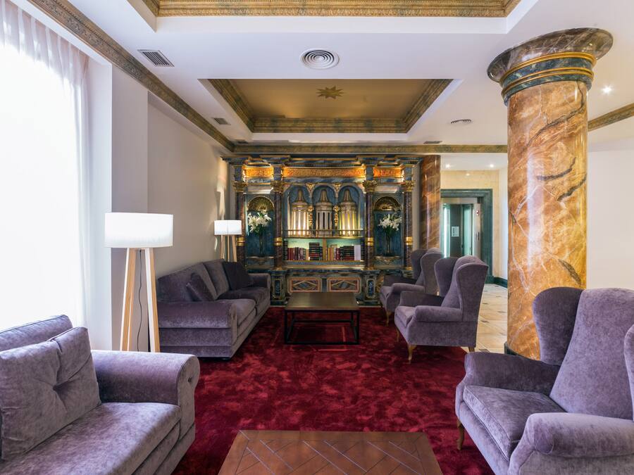 A luxurious lobby with plush seating, a marble column, and an ornate bookcase.