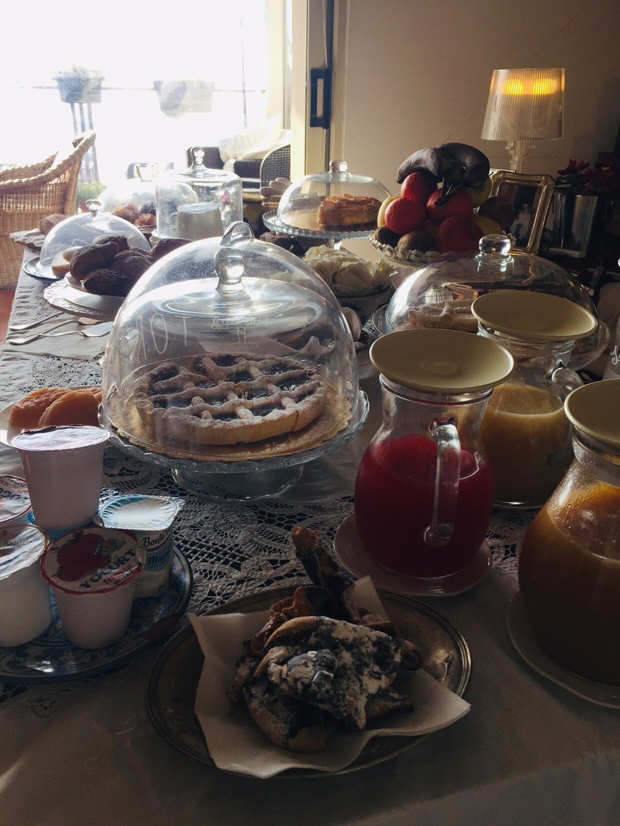 Ein Tisch mit verschiedenen Speisen, darunter Kuchen, Gebäck und Getränke, bedeckt mit Glaskuppeln.