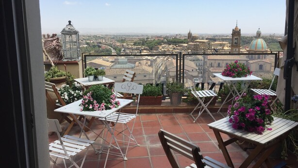 A terrace with tables and chairs, potted plants, and a city view. - Casa Patronale Tipica Siciliana Home B&B TreMetriSoprailCielo camere con vista, colazione terrazzo panoramico (Caltagirone)