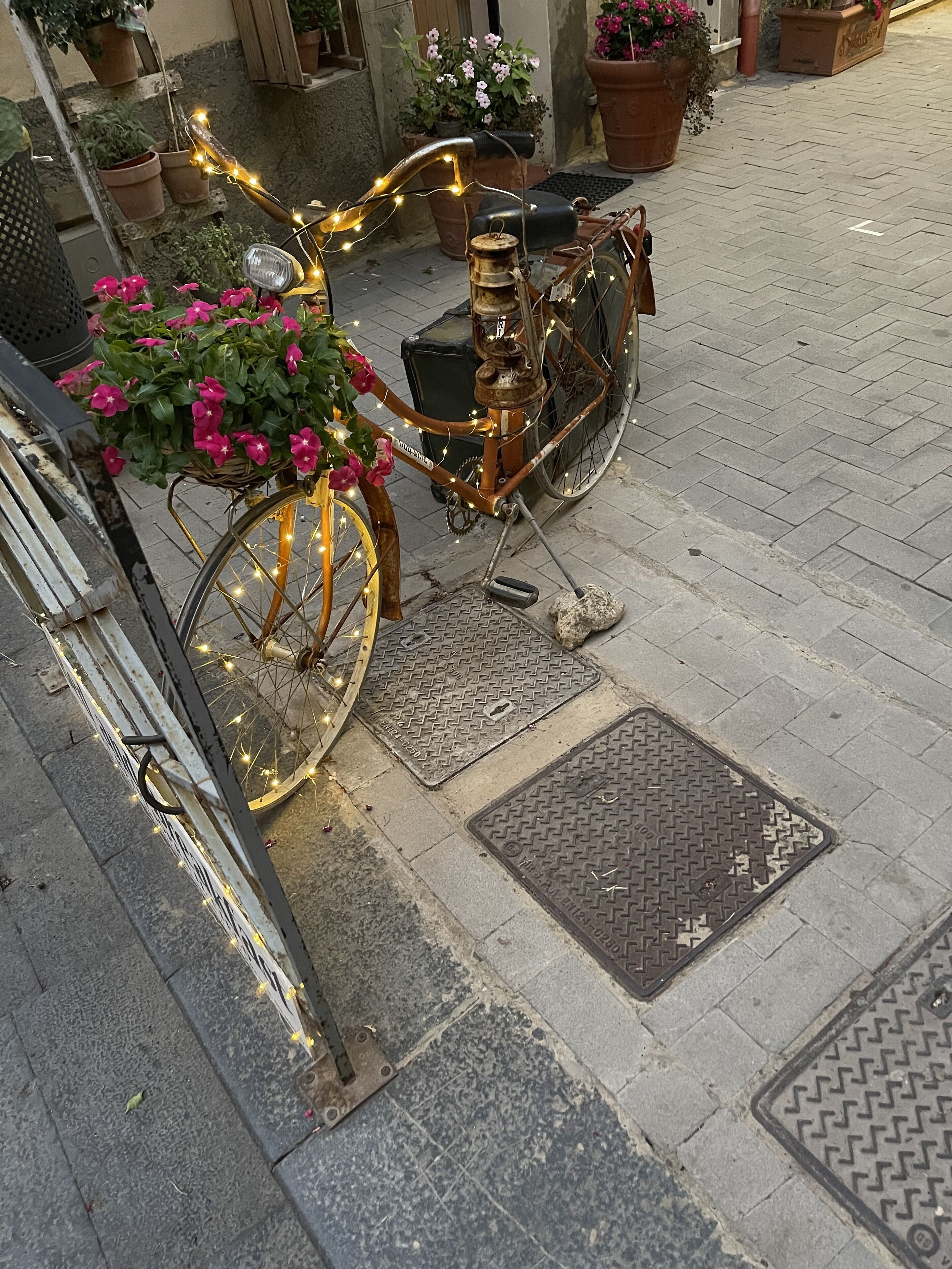 Een fiets met verlichting en een bloemenmandje op een verharde ondergrond.