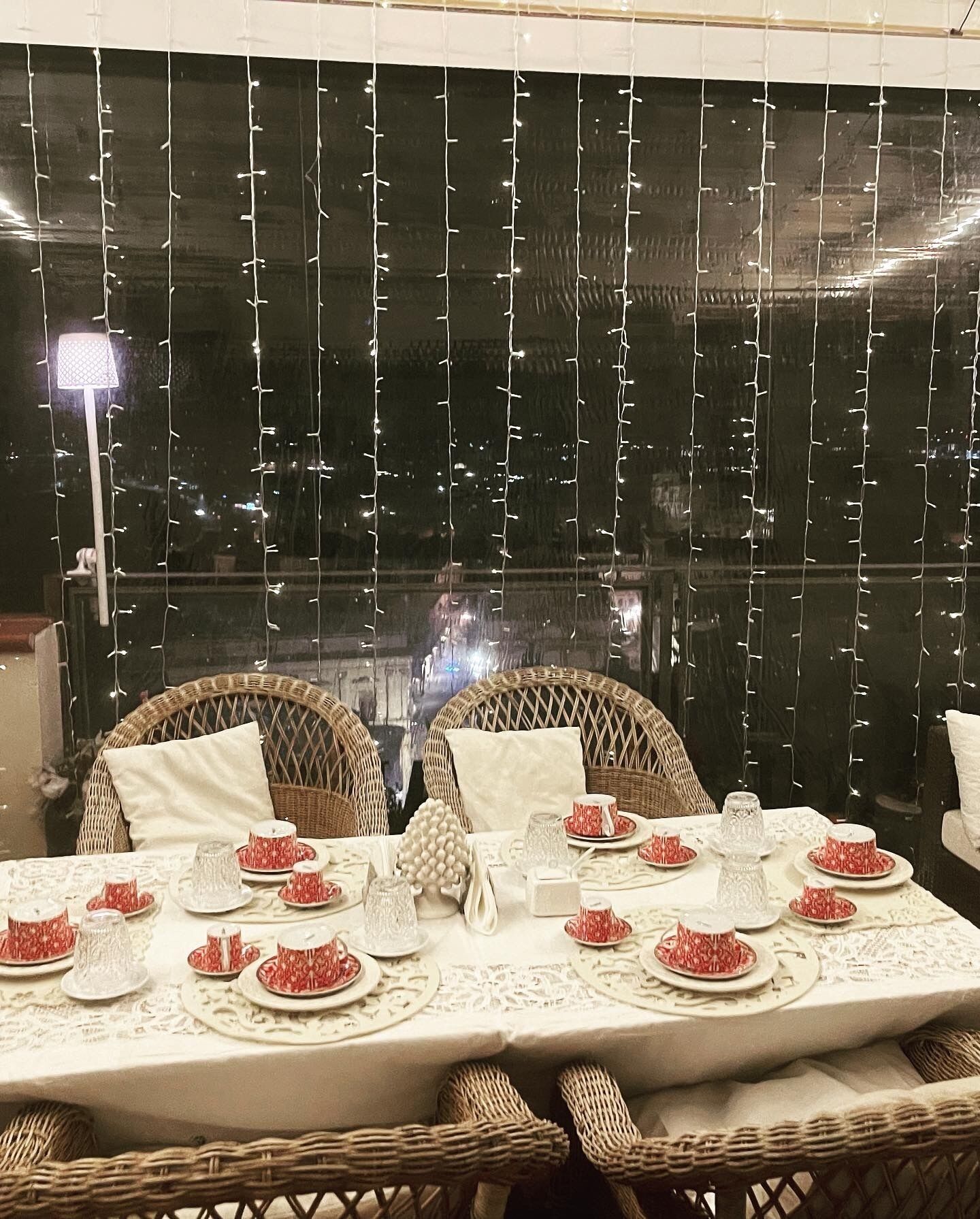 Mesa para cuatro, con mantel blanco y vajilla roja estampada.
