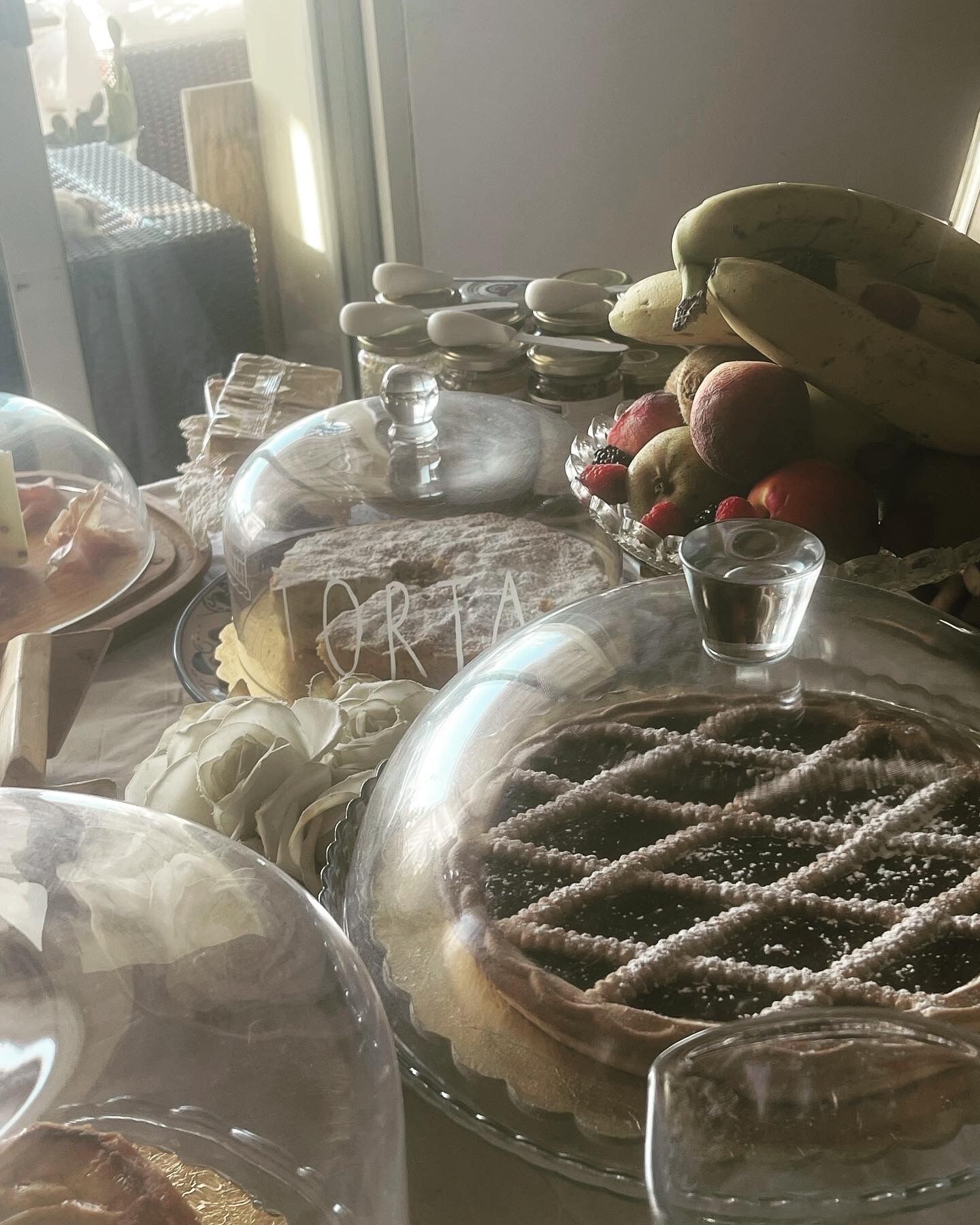 A dessert table with various covered dishes, including a cake labeled "ORTA" and a glass of water.