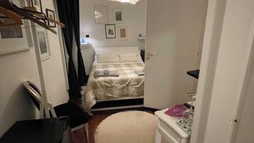 Un dormitorio pequeño y acogedor con cama, mesita de noche y escritorio con silla.