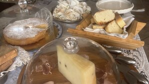 A buffet table with various food items, including a cheese wheel, pastries, and a fruit bowl. - Casa Patronale Tipica Siciliana Home B&B TreMetriSoprailCielo camere con vista, colazione terrazzo panoramico (Caltagirone)